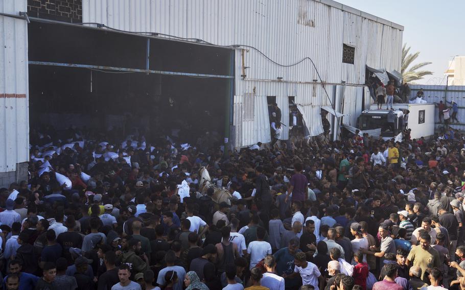 Hundreds of people rushing into a warehouse, with some ripping through the walls.