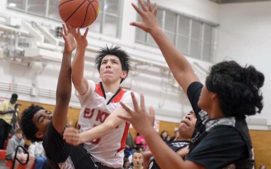 E.J. King's Cameron Reinhart shoots between Zama defenders Ryan Pena, Jarius Brown and Kekua "Rhino" Aumua during Friday's DODEA-Japan boys basketball season-opening game. The Trojans won 57-54.