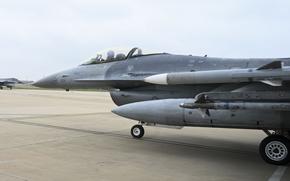A military fighter jet, seen from the side, taxis onto a runway.