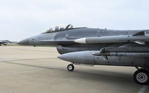 A military fighter jet, seen from the side, taxis onto a runway.