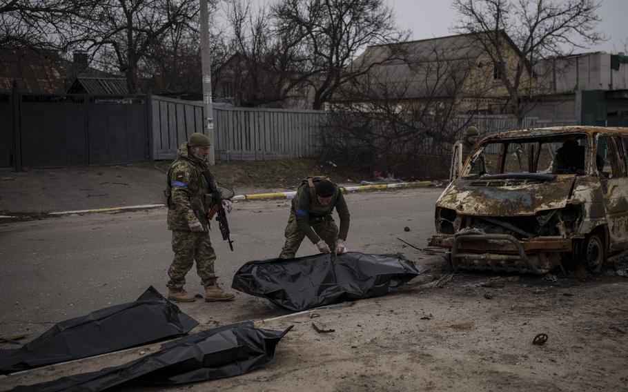 Ukrainian soldiers recover the remains of four killed civilians from inside a charred vehicle in Bucha, outskirts of Kyiv, Ukraine, Tuesday, April 5, 2022. Ukraine’s president plans to address the U.N.’s most powerful body after even more grisly evidence emerged of civilian massacres in areas that Russian forces recently left. 