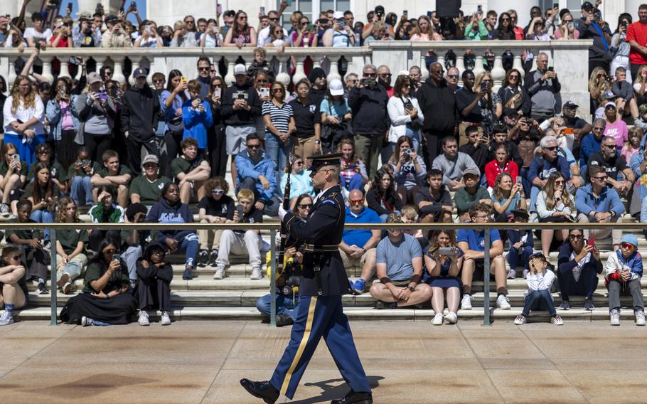 A soldier marches, with his rifle, in front of a crowd.