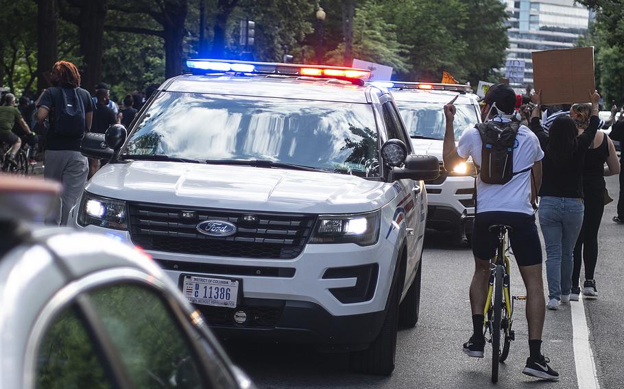 A protester gives the finger while looking inside a police vehicle as he and thousands of other demonstrators marched through the streets of Washington, D.C. within blocks of the White House on Friday, May 30, 2020. The march participants were protesting the death of George Floyd. 