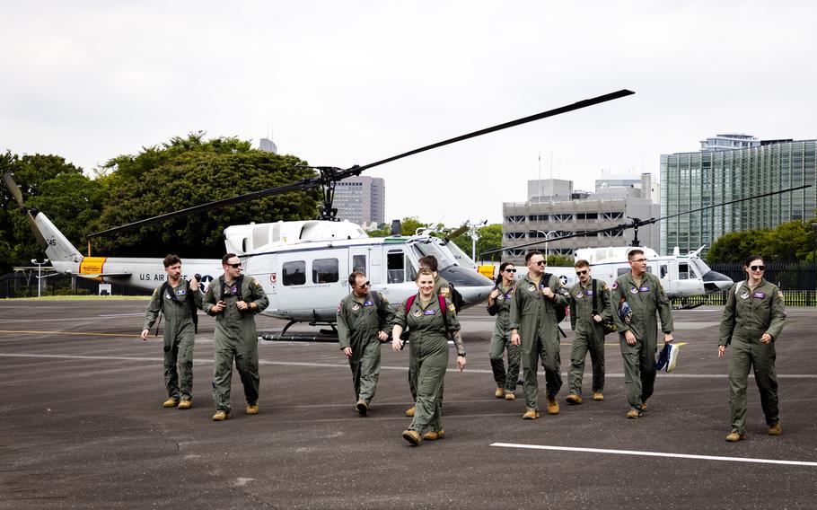  A group of U.S. Air Force personnel in olive green flight suits walk across a helicopter landing pad. 