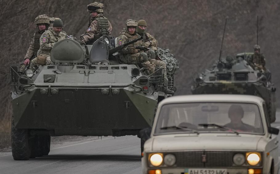 Ukrainian servicemen sit atop armored personnel carriers driving on a road in the Donetsk region, eastern Ukraine, Thursday, Feb. 24, 2022. Russian President Vladimir Putin on Thursday announced a military operation in Ukraine and warned other countries that any attempt to interfere with the Russian action would lead to “consequences you have never seen.”