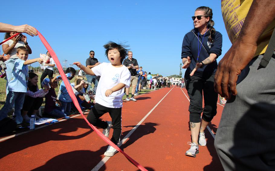 People cheer as a track-and-field athlete crosses the finish line during the Kadena Special Olympics at Kadena Air Base, Okinawa, Dec. 9, 2023. 