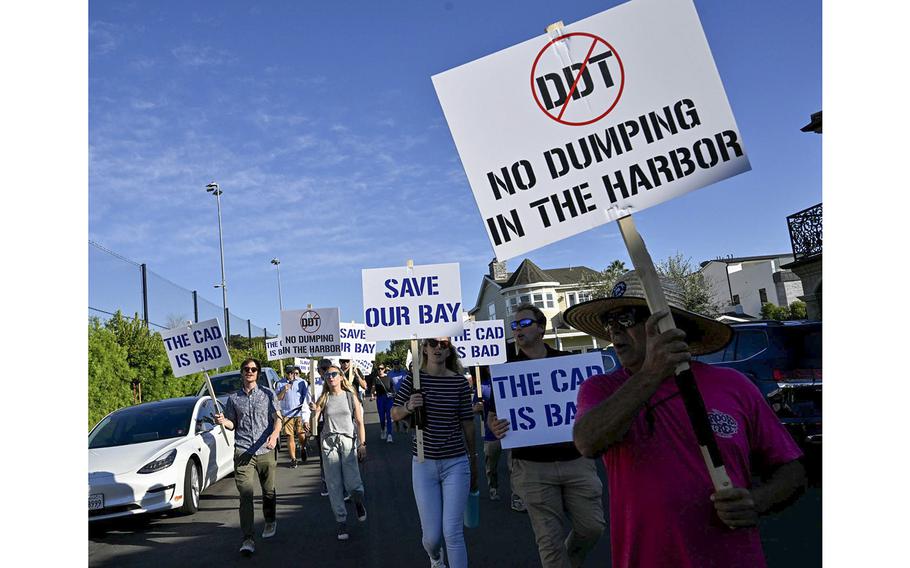 Demonstrators march in Newport Beach, Calif., on Sept. 27, 2022, to protest a proposal to dump contaminated sludge into the center of Newport Harbor.