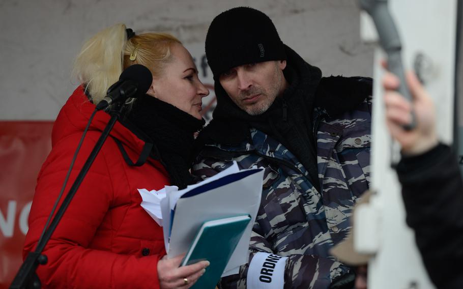 Elena Kolbasnikova and her partner, Max Schlund, talk on stage above a large pro-Russia peace protest in downtown Ramstein-Miesebach, Germany, on Feb. 26, 2023. Together, the couple has been organizing events and protests throughout Germany.