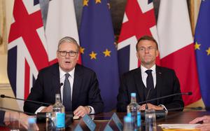 The leaders of the U.K. and France sit on a conference table in suits.
