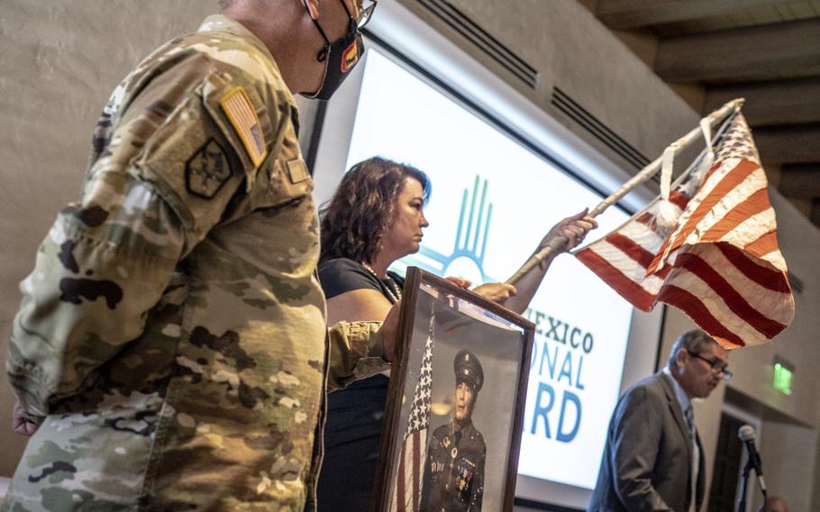 Retired Col. Brian Baca, right, tells New Mexico National Guard soldiers and airmen the incredible story of an American flag made from scraps of material in a Japanese prisoner of war camp during World War II, Sept. 8, 2021 in Albuquerque, N.M.