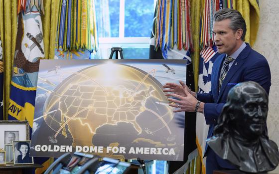 Hegseth stands in front of a poster showing the Golden Dome for America.