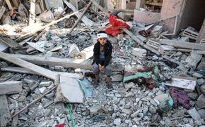 An injured child sits amid the rubble of a destroyed building in Rafah, southern Gaza, on Jan. 18. (MUST CREDIT: Loay Ayyoub for The Washington Post)