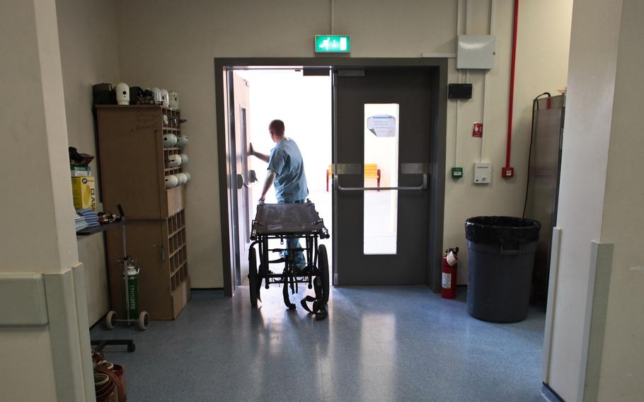 A hospital member wheels a gurney outside a door