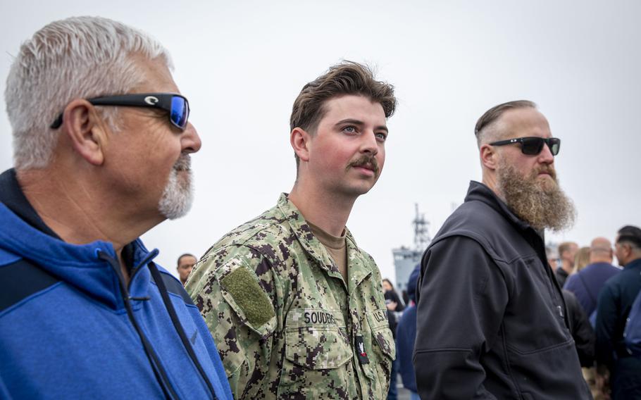 A sailor and two men look out in the distance