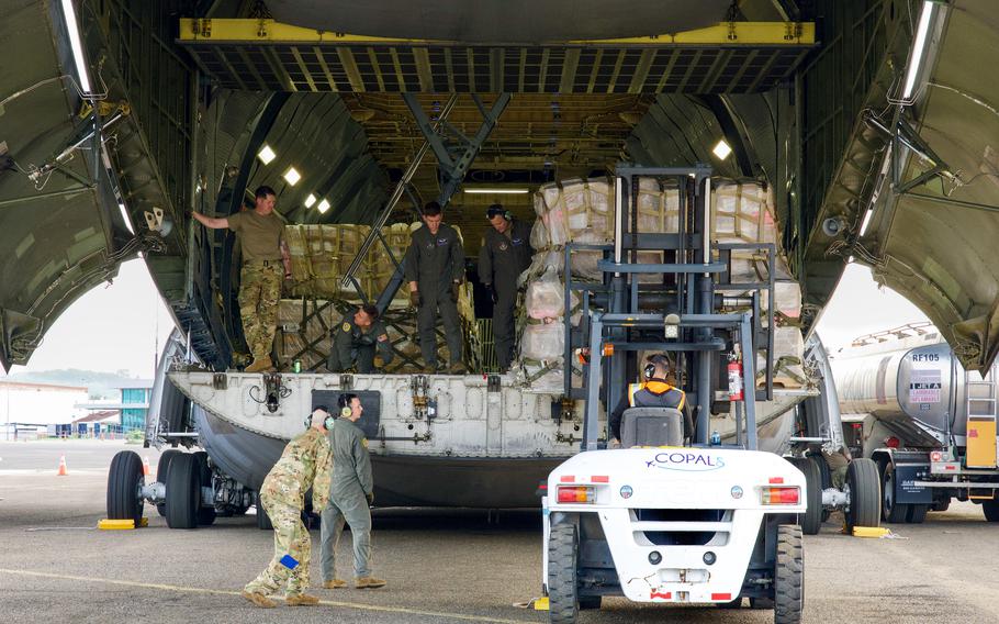 Airmen guide a forklift to offload food pallets.