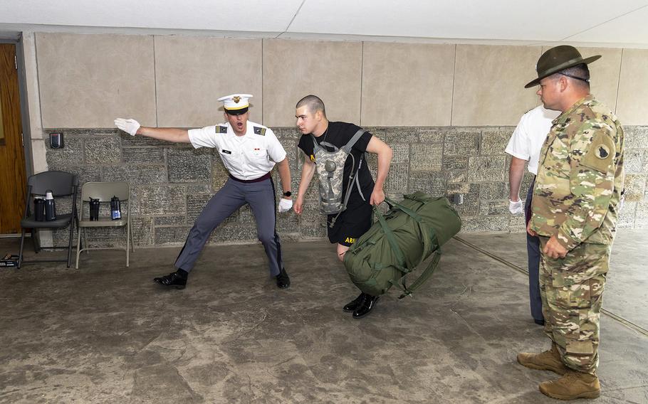 A new cadet hustles after taking an order from a cadet cadre member as a drill sergeant from the 198th Infantry Training Brigade looks on during Reception Day on June 27, 2022, at the United States Military Academy at West Point, N.Y.