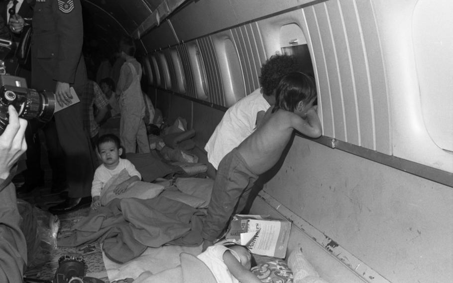 Two young children lean against an airplane window.