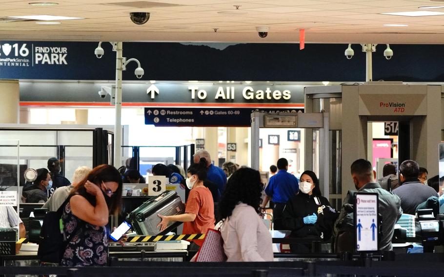 Travelers wearing protective masks are screened at a Transportation Security Administration security checkpoint at Los Angeles International Airport in Los Angeles on May 28, 2021. 