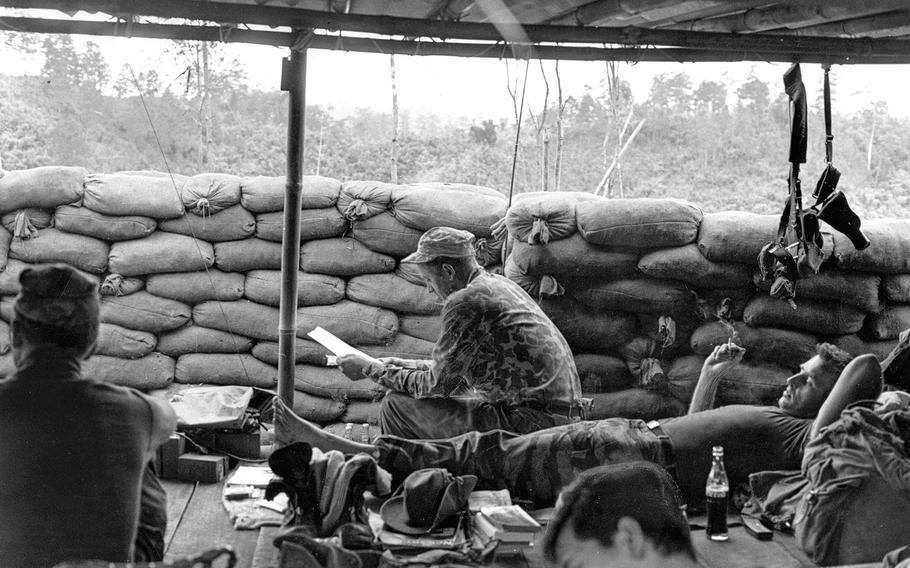 South Vietnam, December, 1963: Staff Sgt. Howard Stevens, center, Special Forces adviser to a Montagnard strike force, reads his mail at Phey-Shuron, a camp being built in Vietnam's Central Highlands. Stevens was part of a 12-man "A-team" attempting to make soldiers of Koho tribesmen in the jungle mountains west of Dalat.