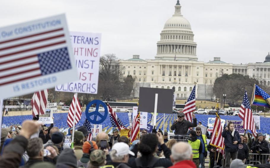 Crowd protests, some holding American flags, in front of the U.S. Capitol.