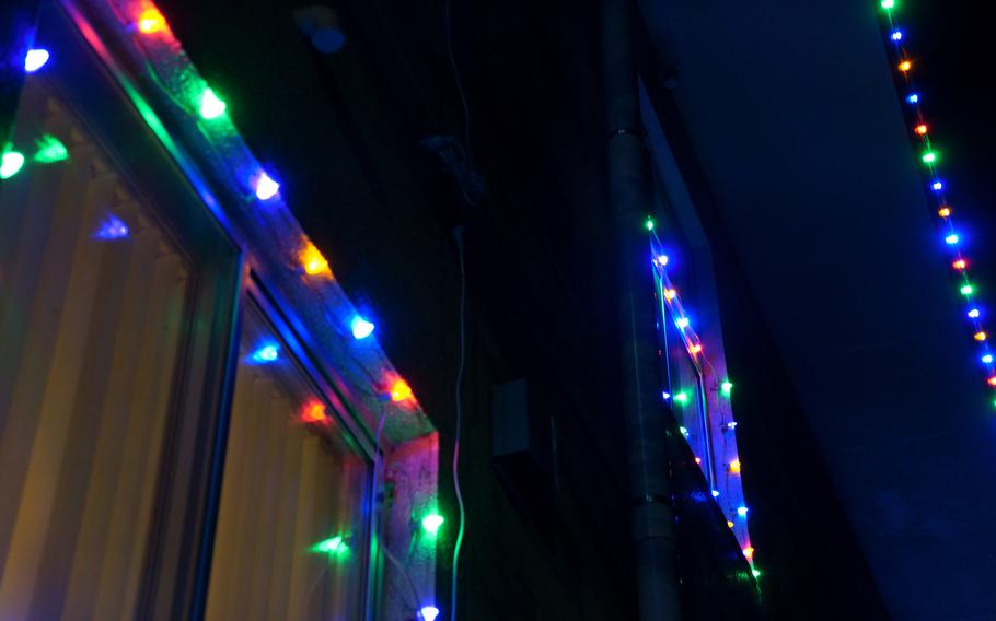 A house illuminated at night with strings of multi-colored Christmas lights around the windows and along the roof.