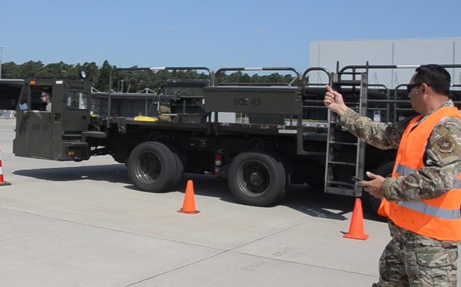 A judge in the 721st Aerial Port Squadron's Multi-Capable Airmen Rodeo at Ramstein Air Base on July 23, 2021, tells Airman 1st Class Ryan Joy to keep driving during an exercise in which competitors drive a Tunner 60K aircraft cargo loader through a course with figure eights and coned-off sharp turns and straightaways.