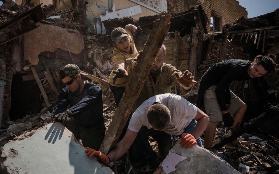 Volunteers clean on May 3 an area in Kharkiv that was destroyed in a strike. 