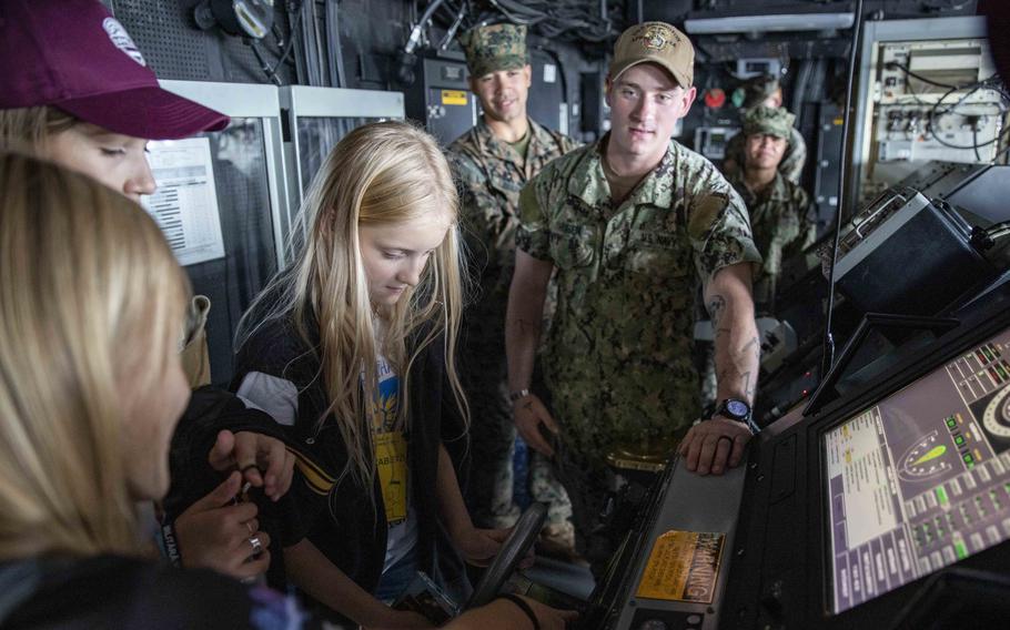 Seaman William Hube explains the steering of the amphibious transport dock ship USS Arlington to a group of Ukrainian children during a port visit in Riga, Latvia, in 2022. Sailors proficient in certain languages, including Ukrainian and Latvian, can earn a $500 bonus by qualifying under a Navy testing program outlined in an April 24 memo. 