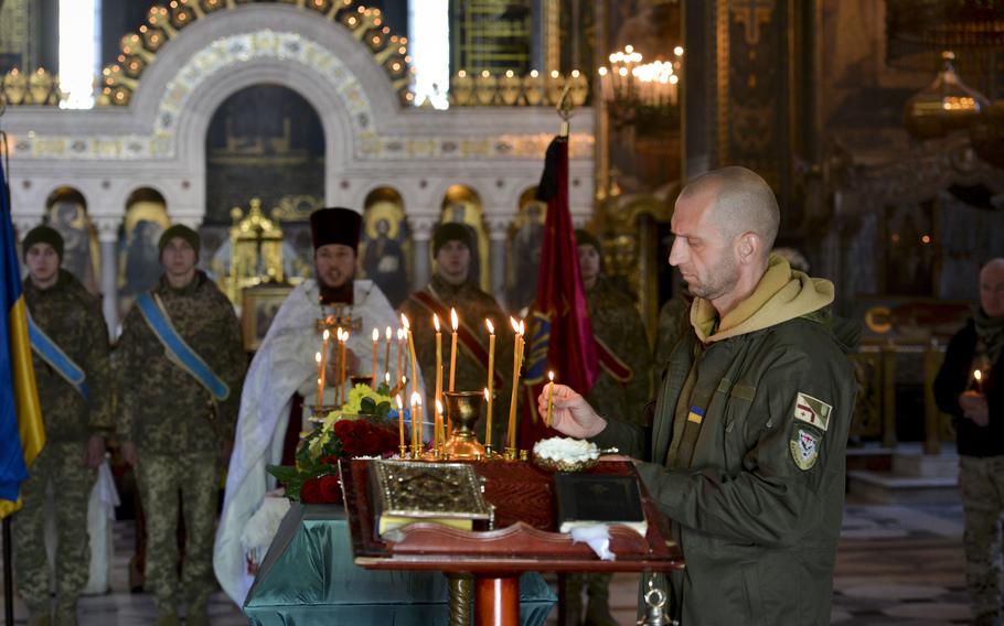 Zurab Dgebuadze, an ethnically Georgian sergeant in the Ukrainian armed forces, places a candle representing a soul into a candelabra near the casket of a fellow soldier at a funeral in Kyiv, Ukraine on Nov. 1, 2022. The soldier, Gurgen Gagnidze, had left his home in the nation of Georgia to fight in Ukraine against Russian forces. 