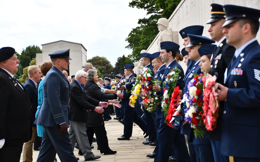 U.S. service members hand off wreaths to locals during the Presentation of Floral Tributes at the end of the Memorial Day ceremony at the Cambridge American Cemetery on Monday, May 30, 2022.