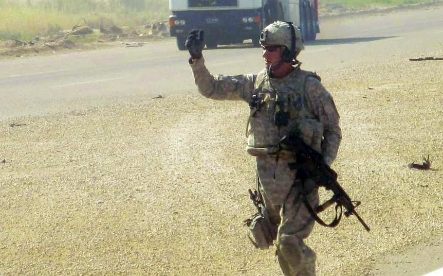 Sgt. Michael Ashby waves to a soldier after hooking up a broken down truck outside Baghdad, Iraq, in 2011. 