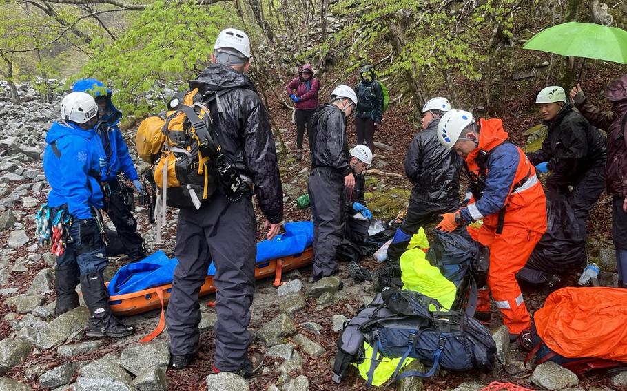 Emergency responders work to evacuate a Japanese man injured near Mount Hinokiboramaru in Kanagawa prefecture, April 15, 2023. 
