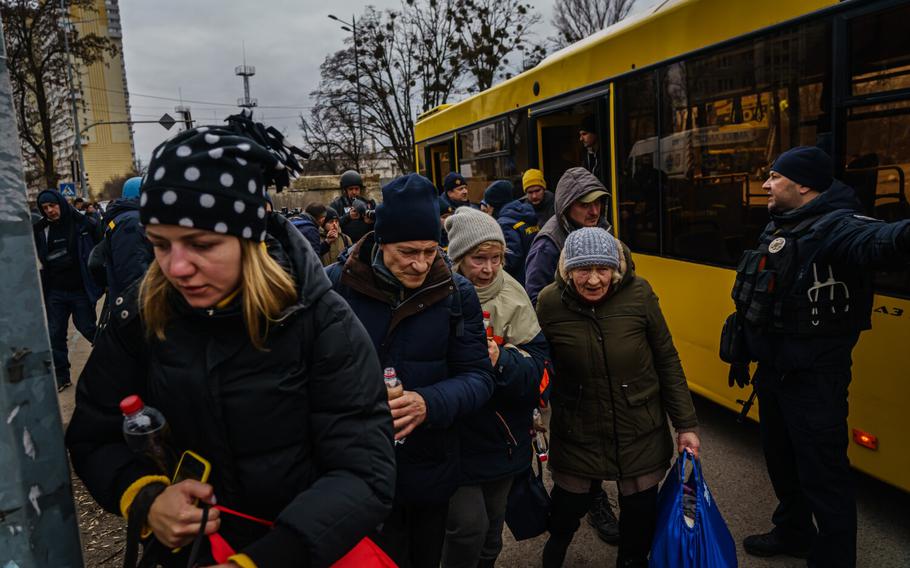 Local residents exit evacuation buses after their town was bombarded with Russian artillery fire in Irpin, Ukraine, Sunday, March 6, 2022.