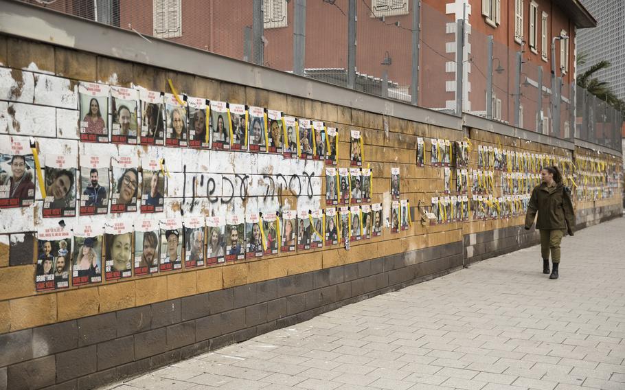An Israeli soldier walks by a wall in Tel Aviv with photos of hostages held by Hamas in the Gaza Strip on Jan. 30, 2024.
