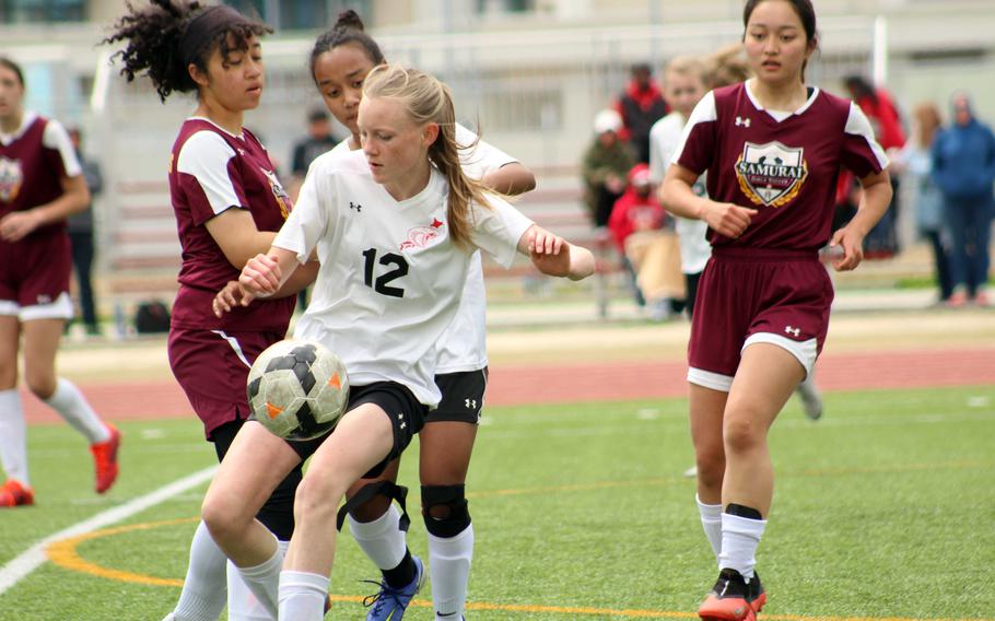 E.J. King's Addison Auger tries to settle the ball against Matthew C. Perry's Tida Curley and Towa Albsmeyer during Saturday's DODEA-Japan soccer match. The teams tied 2-2.