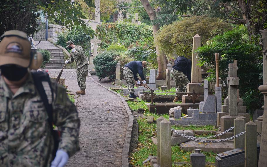 Sailors from Yokosuka Naval Base, Japan, clean up grounds dedicated to American veterans buried at Yokohama Foreign General Cemetery, Wednesday, Nov. 10, 2021. 