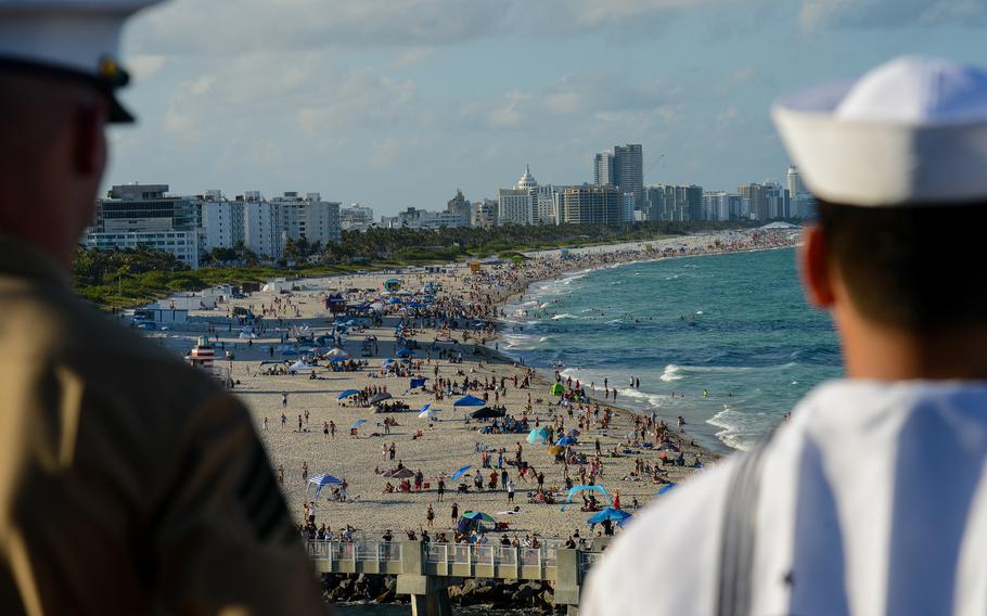 A sailor and a Marine look out over Miami beach from the USS Bataan amphibious assault ship as it pulls into the port of Miami for Fleet Week on Sunday, May 5, 2024. 