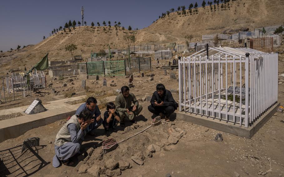 The Ahmadi family pray on Monday, Sept. 13, 2021, at the cemetery next to the graves of family members killed by a US drone strike, in Kabul, Afghanistan.
