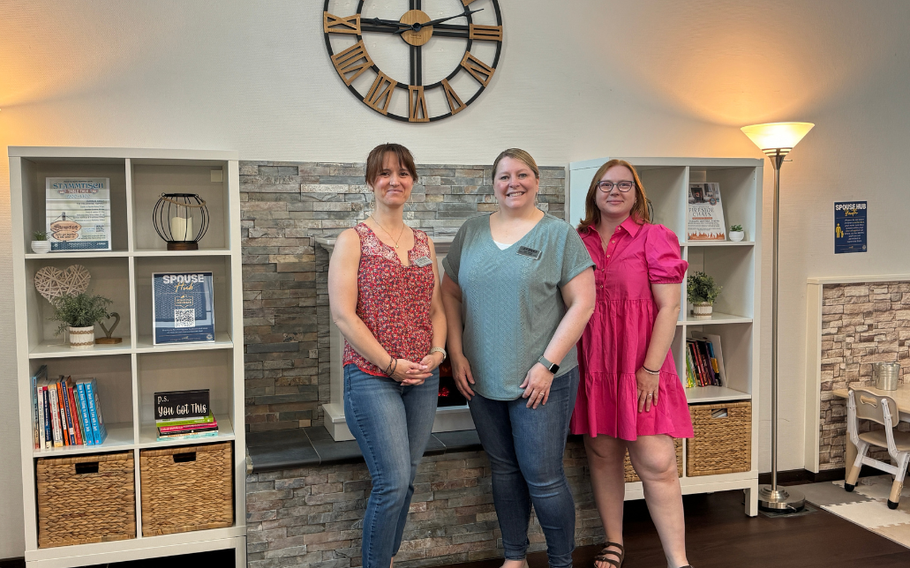 Spouse hub volunteers standing in front of fire place