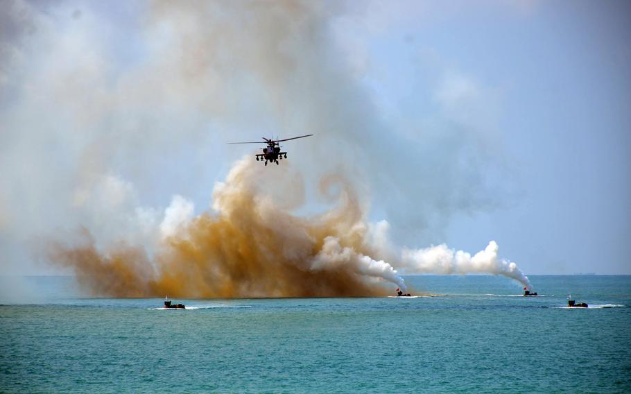 An AH-64 Apache helicopter flies past a smokescreen made by U.S., Thai and South Korean troops during a Cobra Gold amphibious assault on Hat Yao Beach, Thailand, March 1, 2024. 