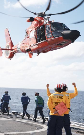 U.S. Coast Guard members assigned to Coast Guard Cutter Thetis and an MH-65 Dolphin helicopter crew from the Helicopter Interdiction Tactical Squadron execute in-flight refueling evolutions, Jan. 31, 2024, in the Central Caribbean Sea. 