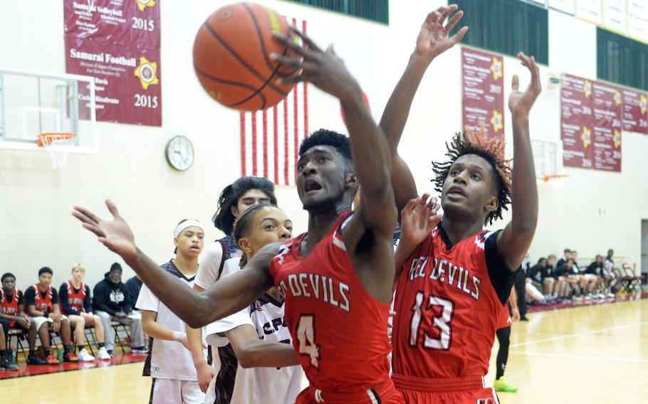 Nile C. Kinnick's Kennedy Hamilton snares a rebound in front of teammate Jaelin White against Matthew C. Perry during Friday's DODEA-Japan boys basketball game. The Red Devils won 67-29.