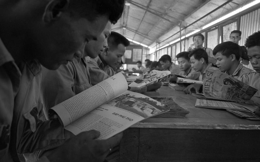 Male POWs read magazines in the prison library at Bien Hoa. They also have radio and television privileges.