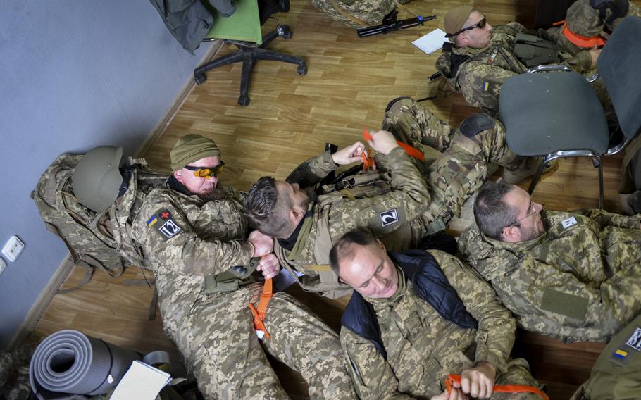 Ukrainian special forces soldiers jump from their seats and dive onto the floor as they rush to put on tourniquets during first aid training at a site outside Kyiv, Ukraine, on Oct. 27, 2022. Each troop must place the tourniquet on themselves within 30 seconds, the point at which blood loss can impair the brain’s ability to function.