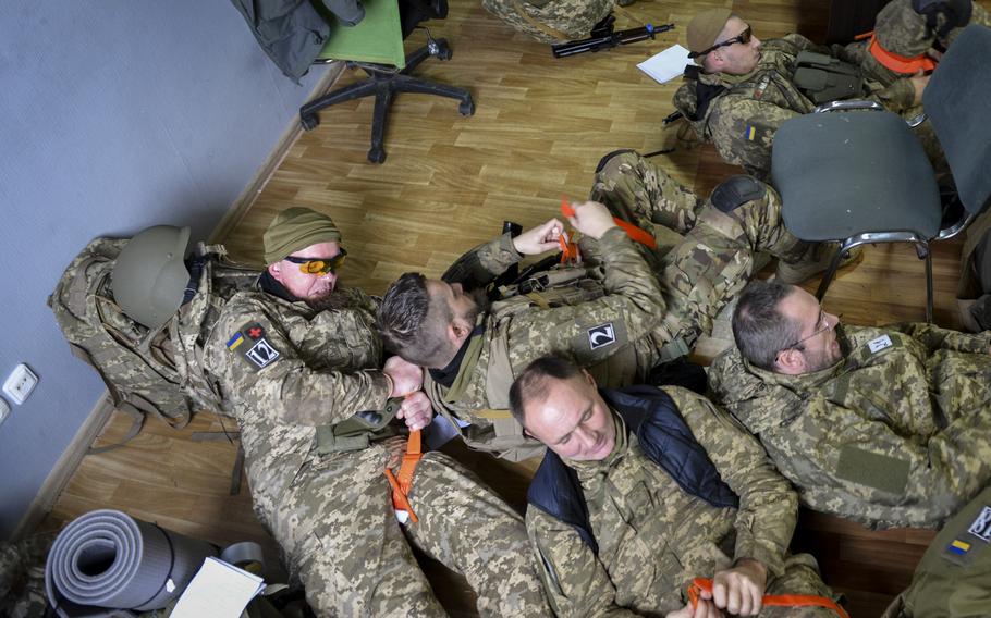 Ukrainian special forces soldiers jump from their seats and dive onto the floor as they rush to put on tourniquets during first aid training at a site outside Kyiv, Ukraine, on Oct. 27, 2022.