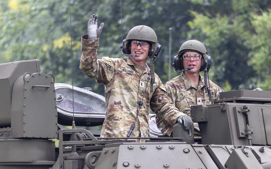 Two soldiers atop a tank waving.