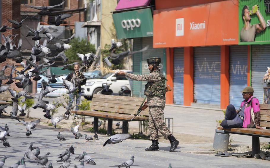 An Indian soldier feeds pigeons at a market.