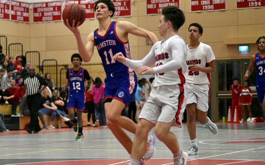 Ramstein's Michael Gonzales travels down the lane while Raider Logan Bell defends during a Jan. 31, 2024, game at Kaiserslautern High School in Kaiserslautern, Germany.