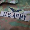 A close-up view of a badge reading “U.S. Army” on a camouflage uniform.