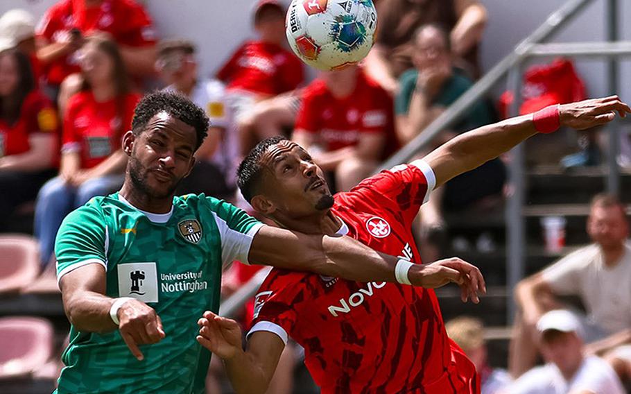 Two soccer players go for the ball.
